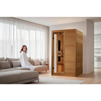 Woman in a white robe standing in a modern living room with a wooden sauna.