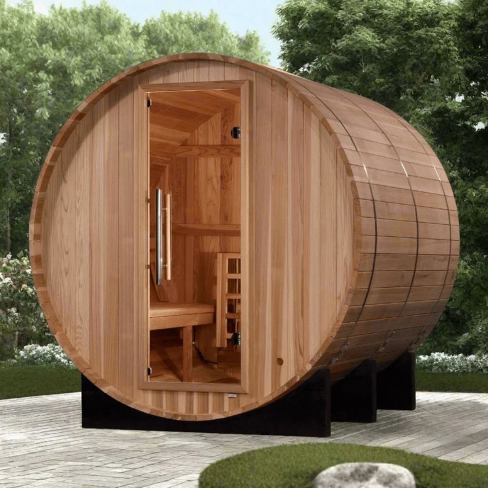 Wooden barrel-shaped sauna in an outdoor setting with trees and grass.