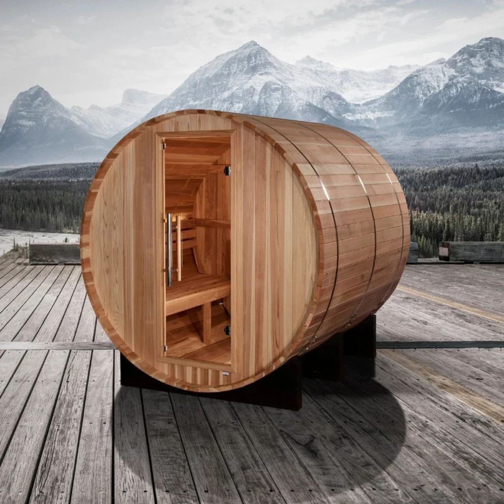 Wooden barrel-shaped sauna on a wooden deck with mountainous landscape in the background