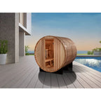 Wooden barrel-shaped sauna on a deck with a pool and garden in the background