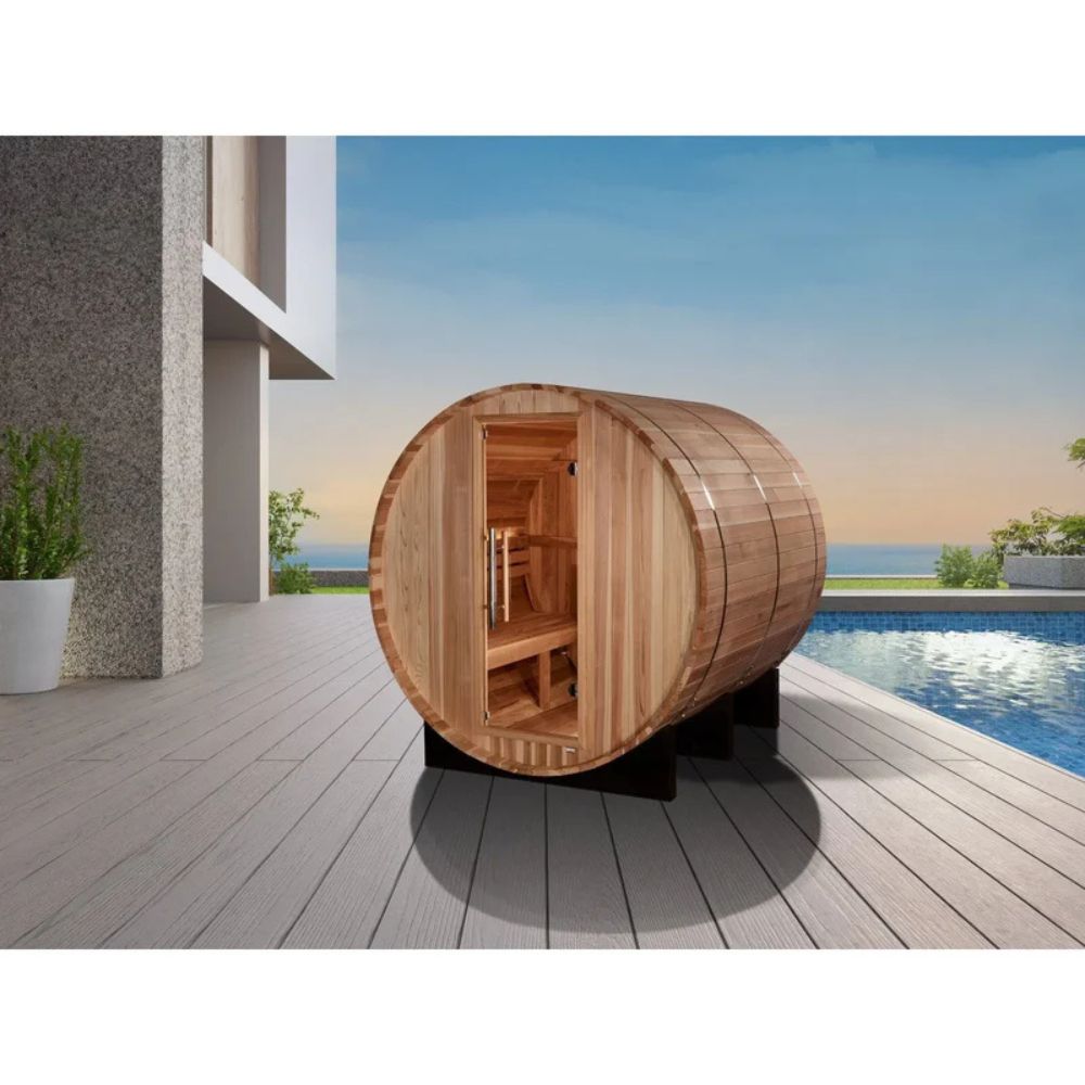 Wooden barrel-shaped sauna on a deck with a pool and garden in the background