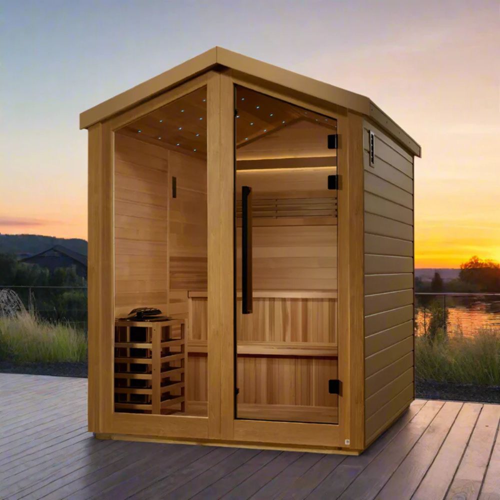Wooden sauna on a wooden deck with a scenic background of a sunset over water.