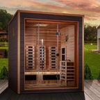 Wooden sauna with glass doors on a wooden deck, surrounded by greenery.