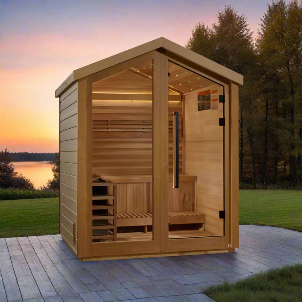 Wooden outdoor sauna with a scenic background of trees and water at sunset.