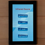 Infrared sauna control panel with touch screen interface on a wooden surface