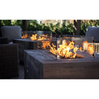 Outdoor fire pit table with flames in a garden setting